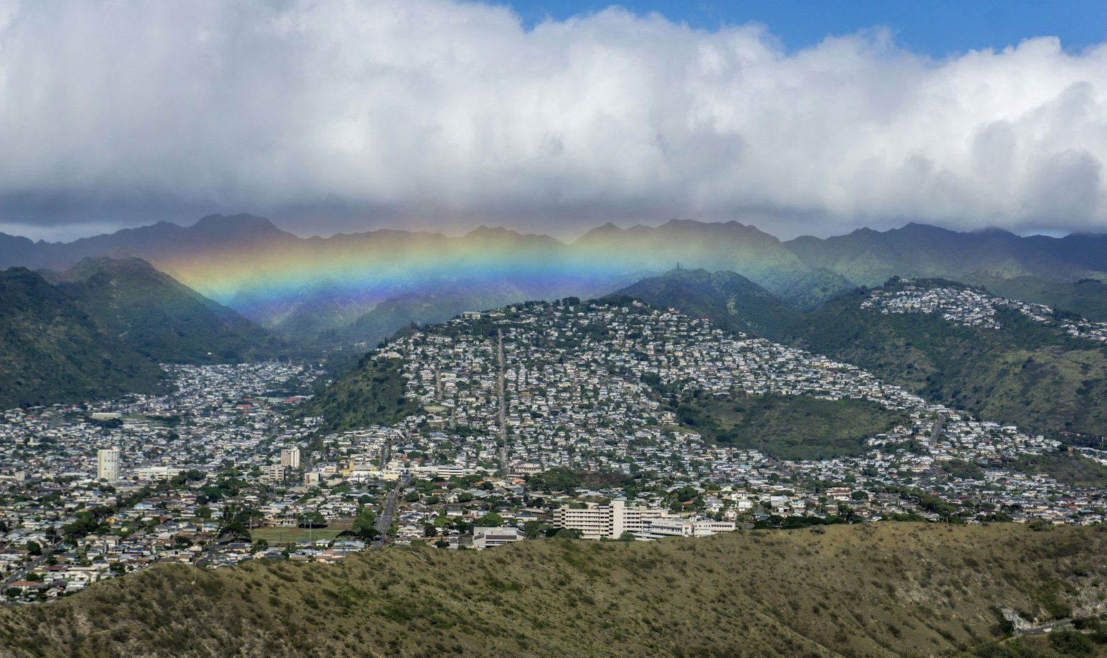 Rainbow over Honolulu neighborhoods under passing rain clouds