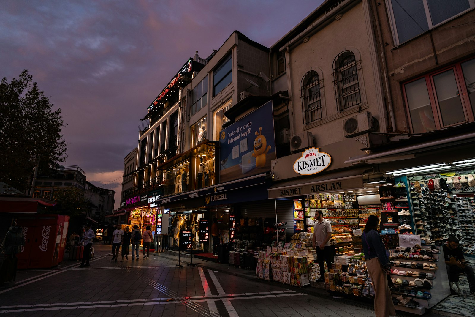 A short street of small shops lit up at dusk
