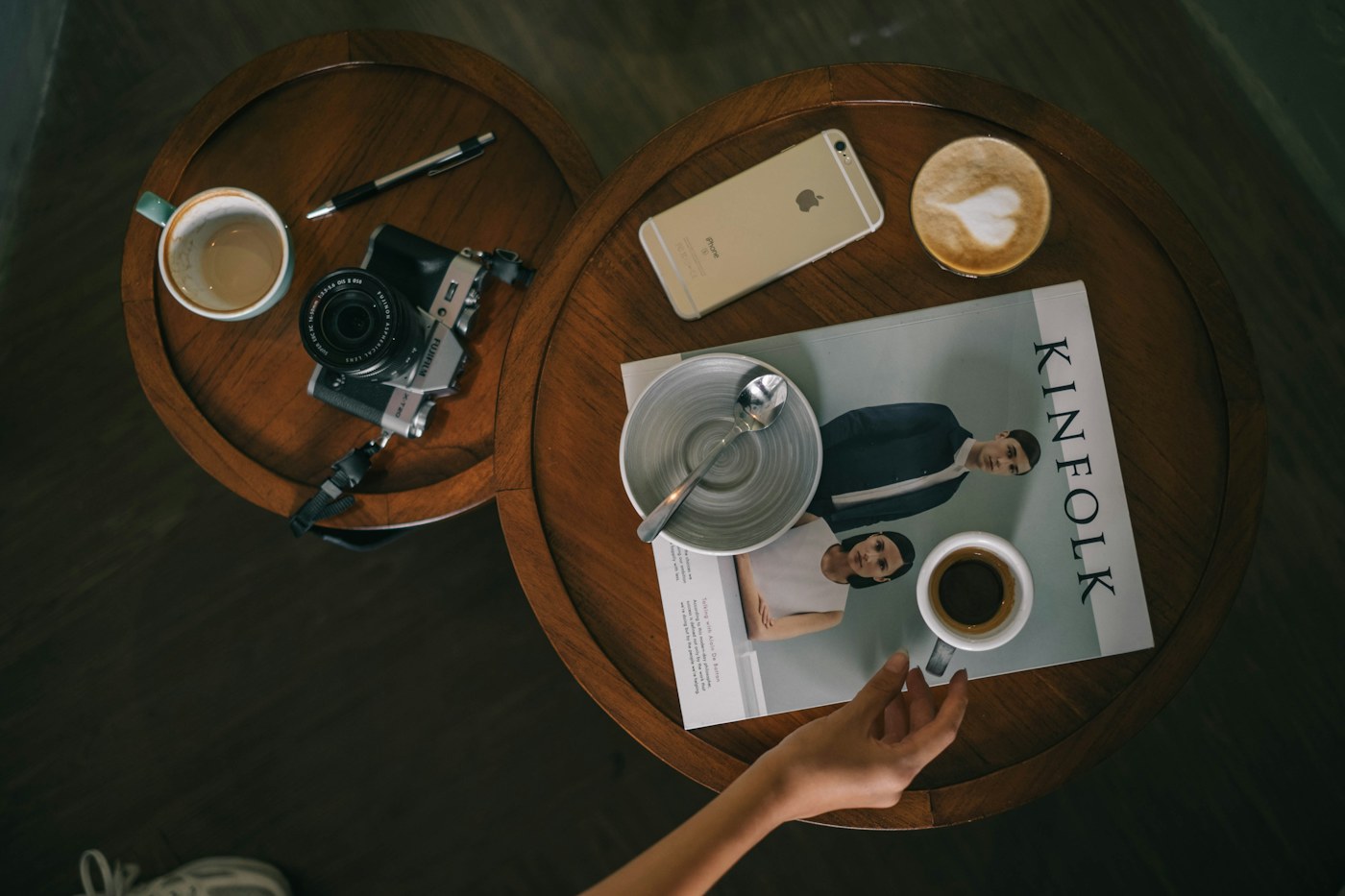 Coffee cups, a camera, and a magazine on small cafe tables
