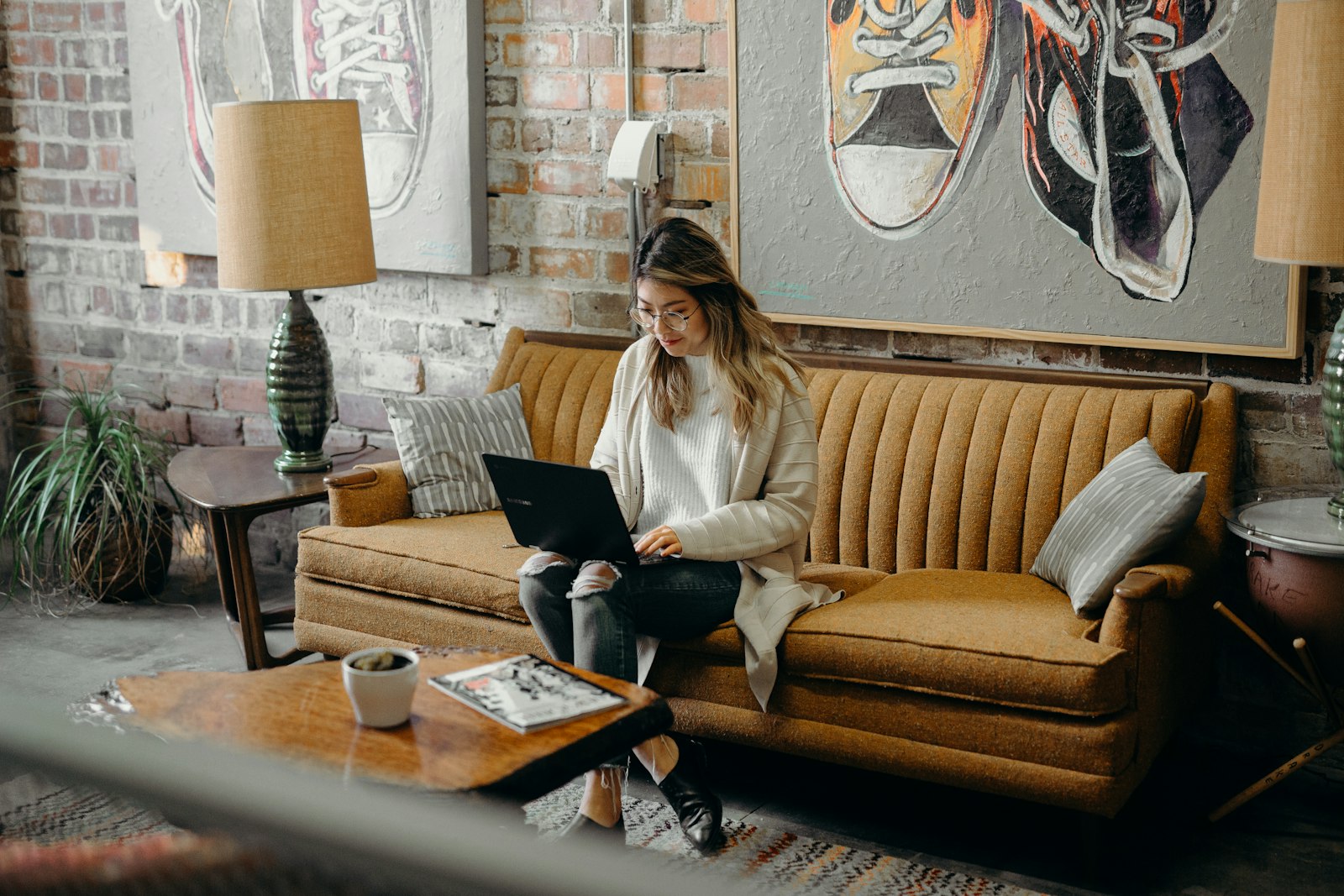 A person working alone on a laptop on a sofa