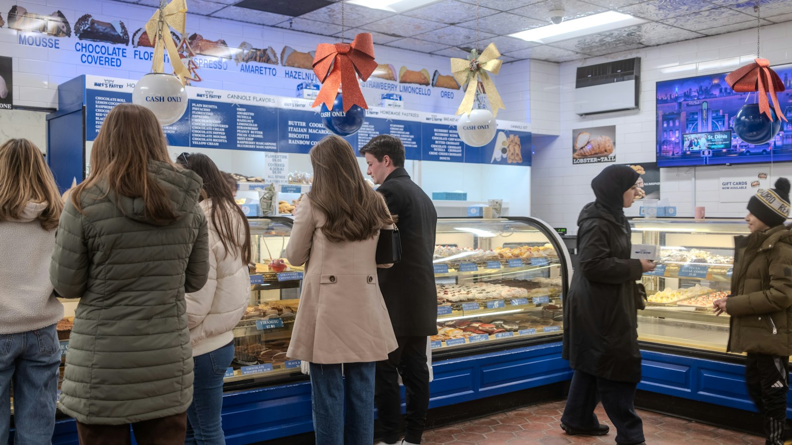 Customers in a bakery looking at pastries behind the counter, the kind of wait the Leonard's Bakery line is about.