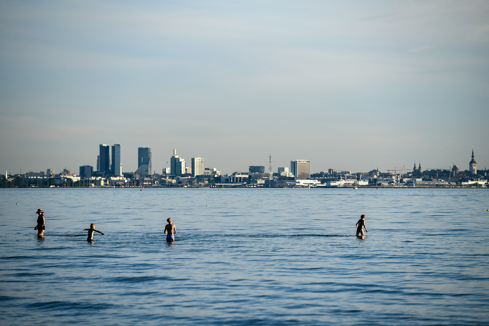 Swimmers in calm water with a city skyline behind them