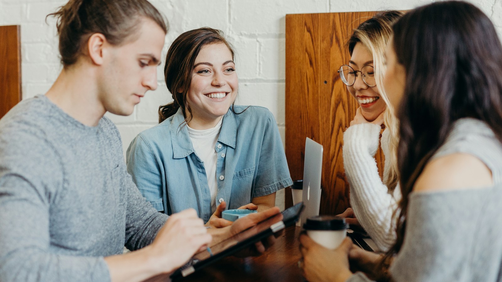 Four people talking around a table with notebooks.