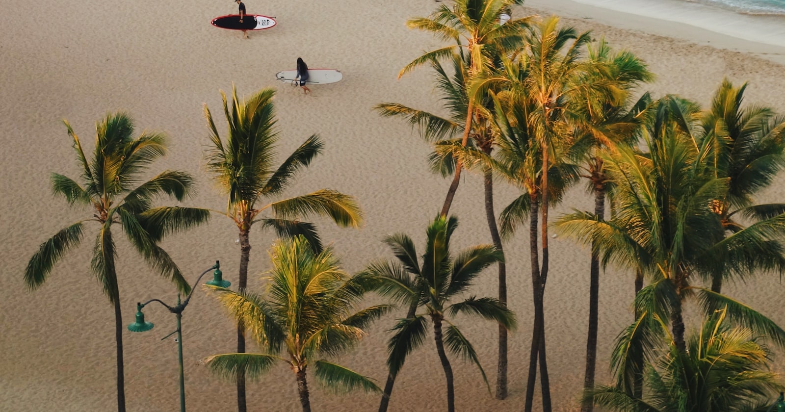 Two people carrying surfboards along the shore in Honolulu, Hawaii — doing what you love, together.
