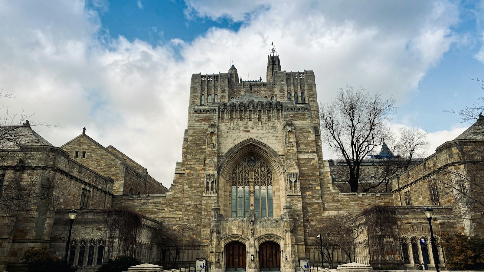 An ornate stone entrance beneath a tower and a cloudy sky.
