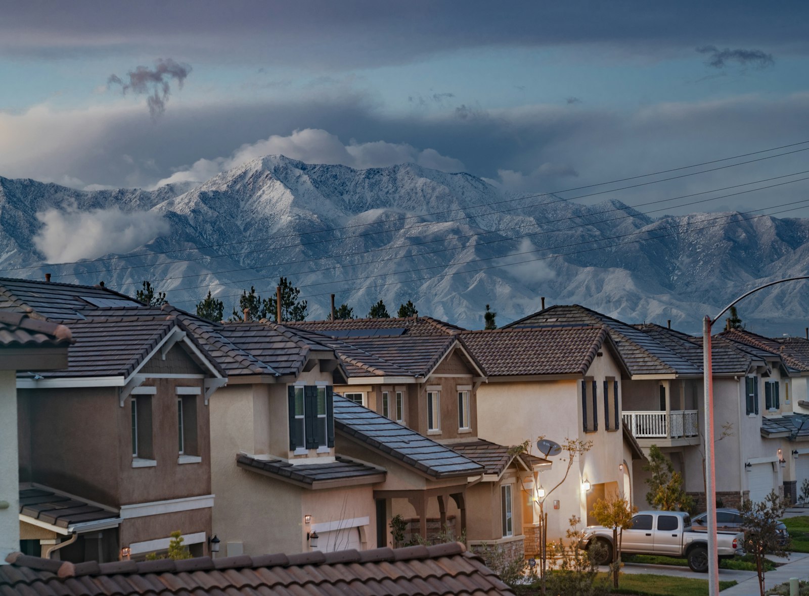 Houses packed close together on a hillside with cloud coming down over the ridge behind.