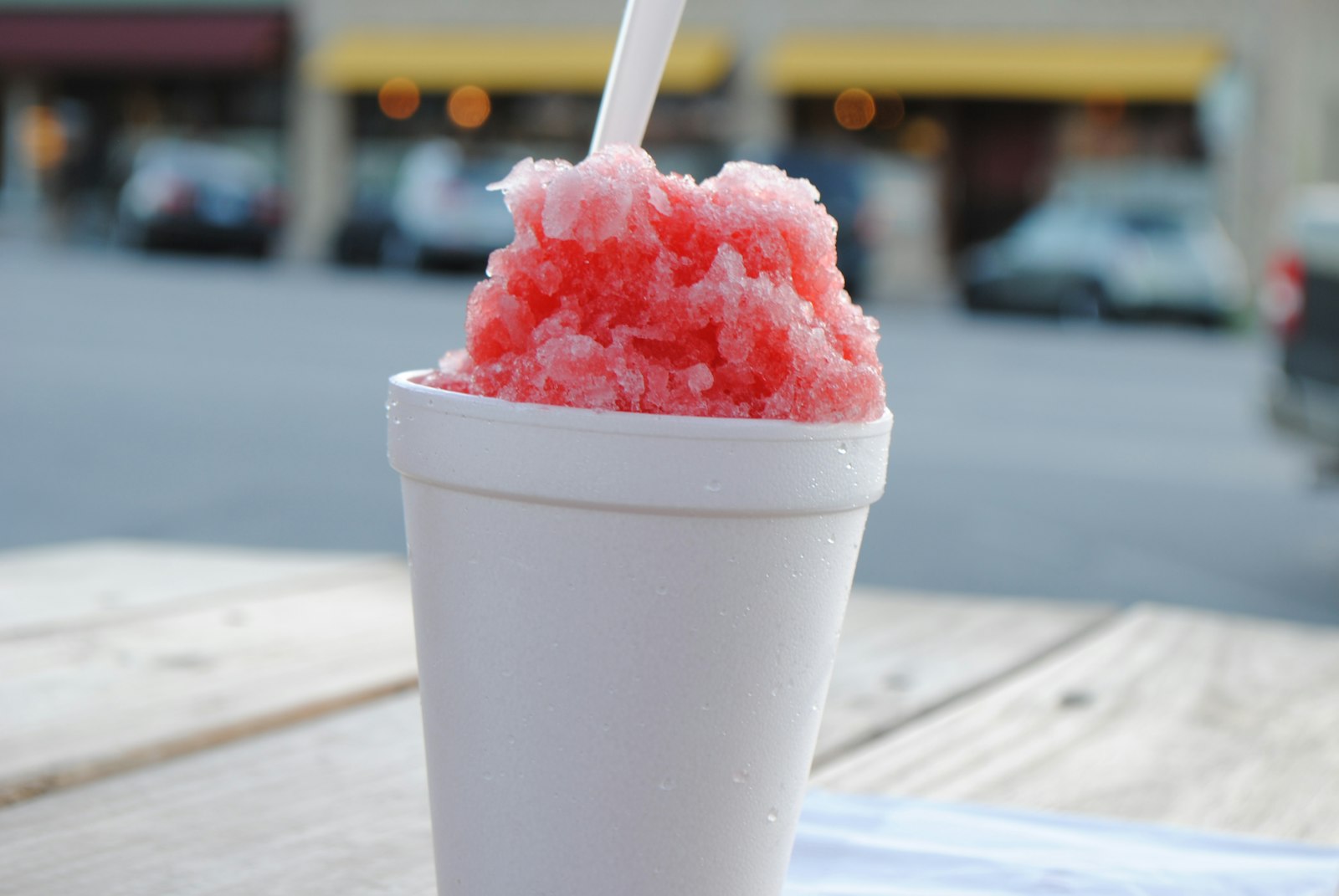 A cup of shave ice held outdoors on a sunny day
