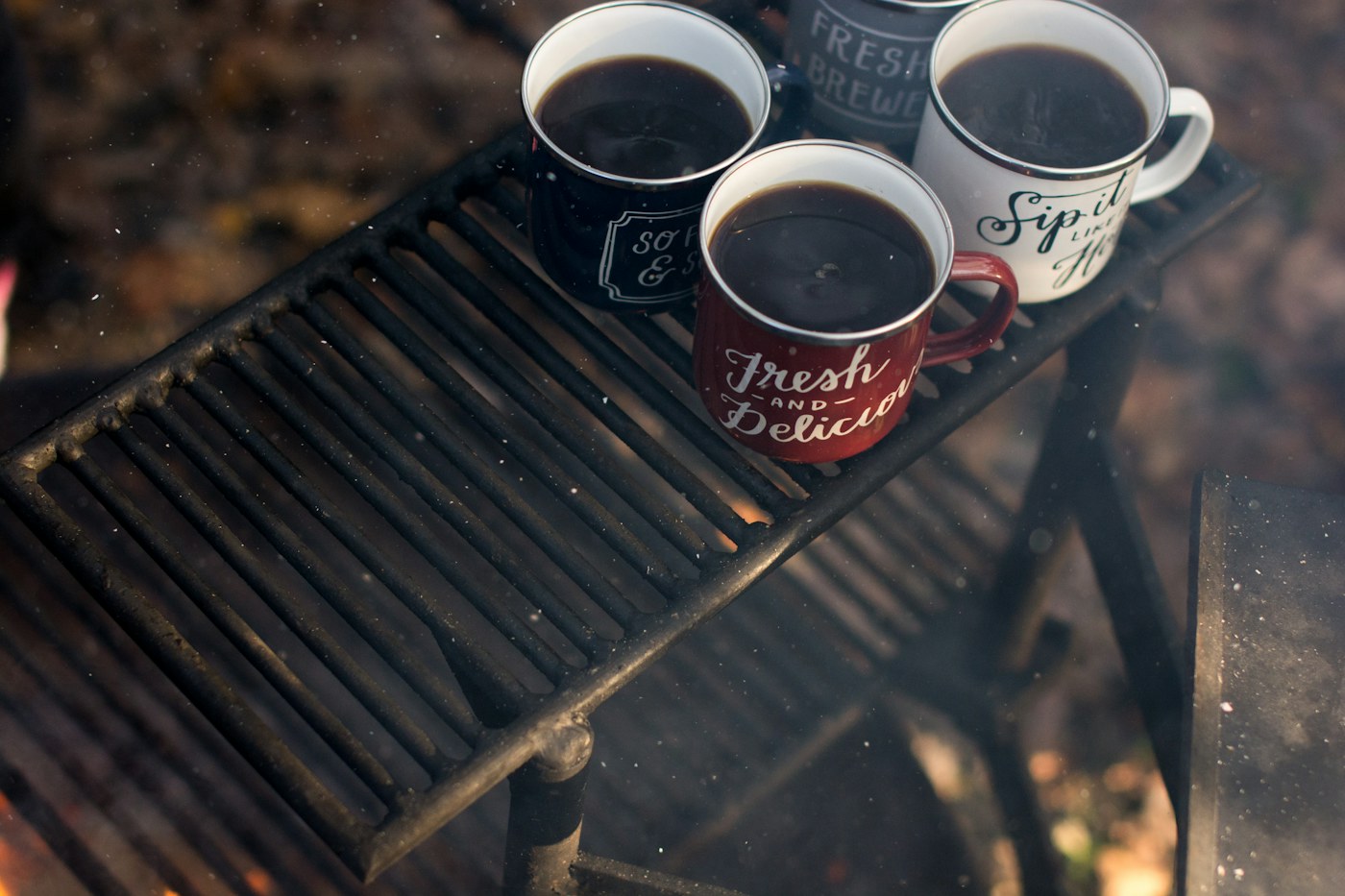 Four mugs of coffee on a metal outdoor table