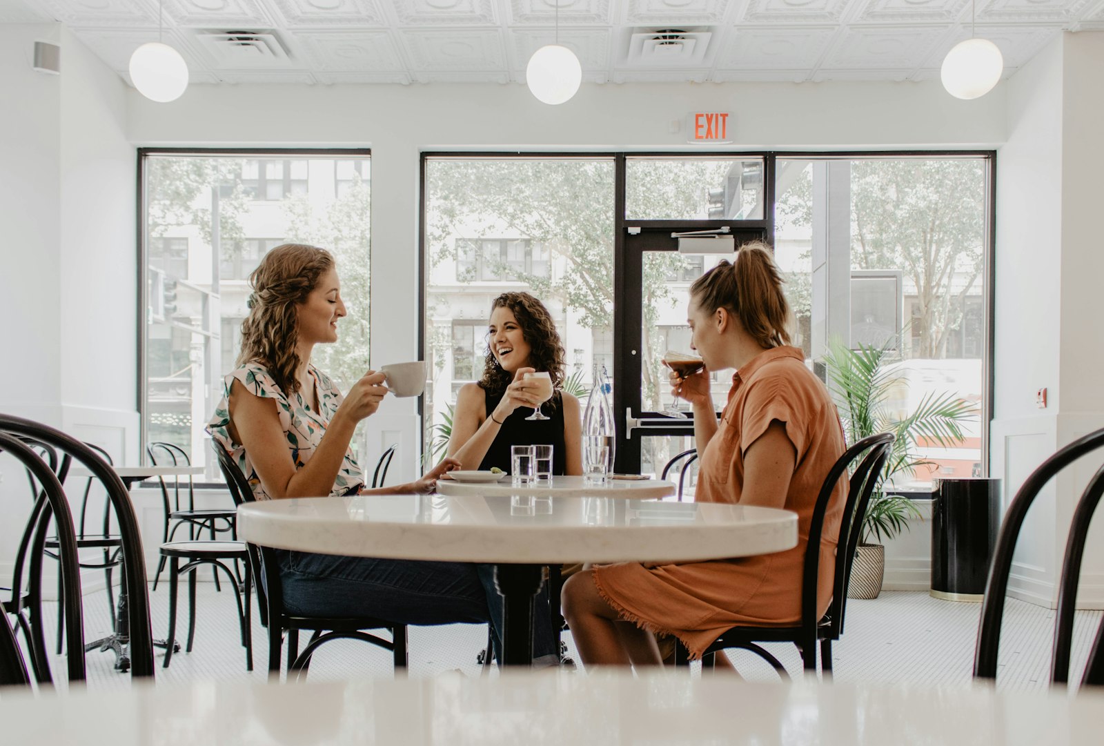 Three people talking over coffee at a cafe table