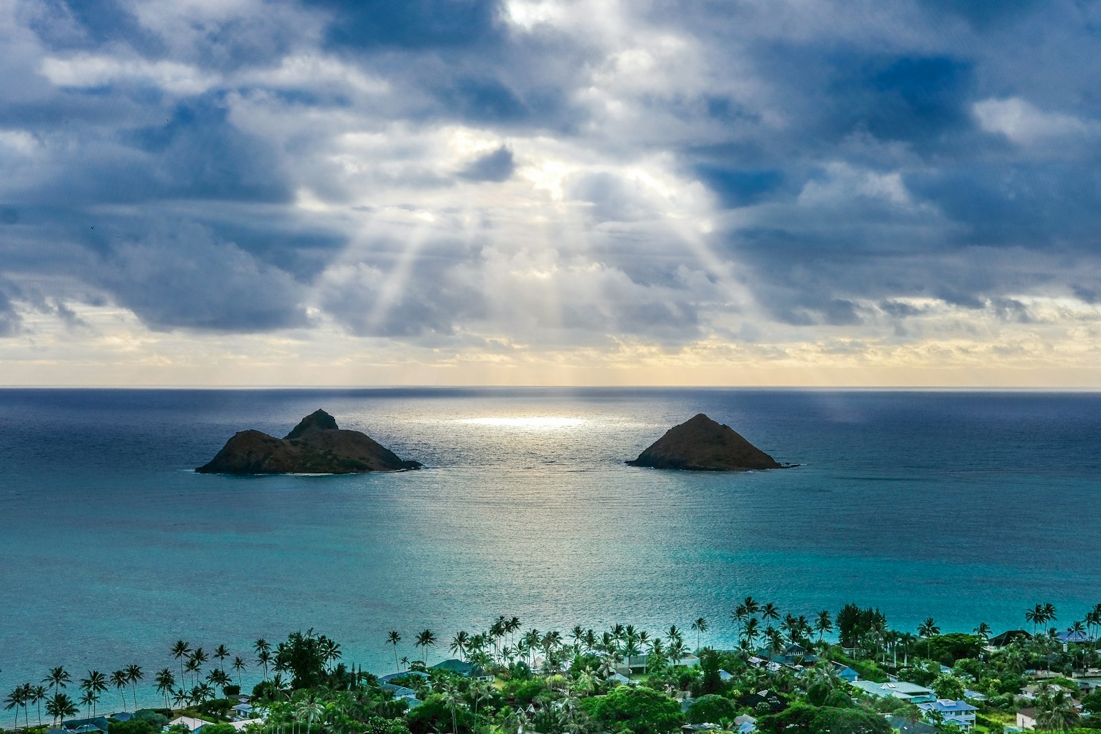 Sunbeams breaking through clouds over the Mokulua islands off Lanikai and Kailua, Oahu.