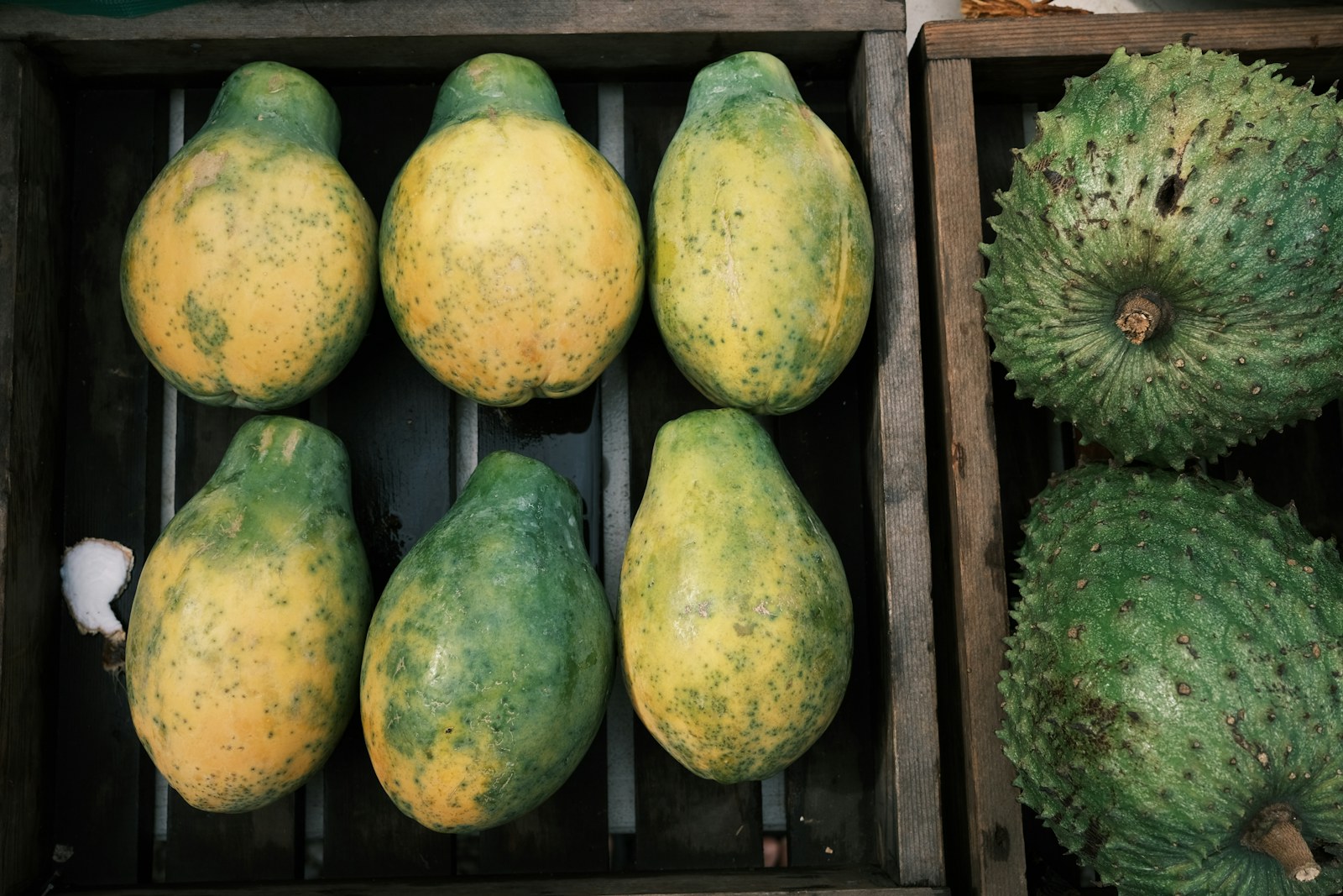 Ripe papayas and soursop stacked in wooden crates at one of the Oahu farmers markets.
