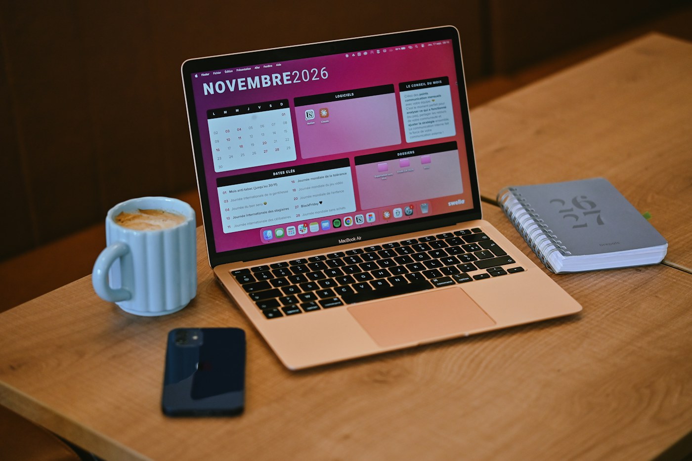 A laptop calendar beside a coffee mug and notebook
