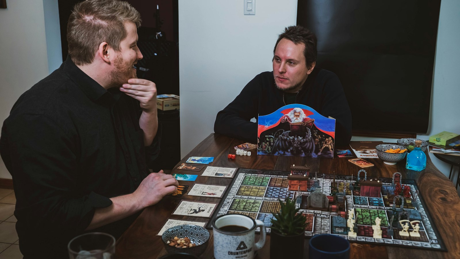 Two people leaning over a board game mid-play at a table