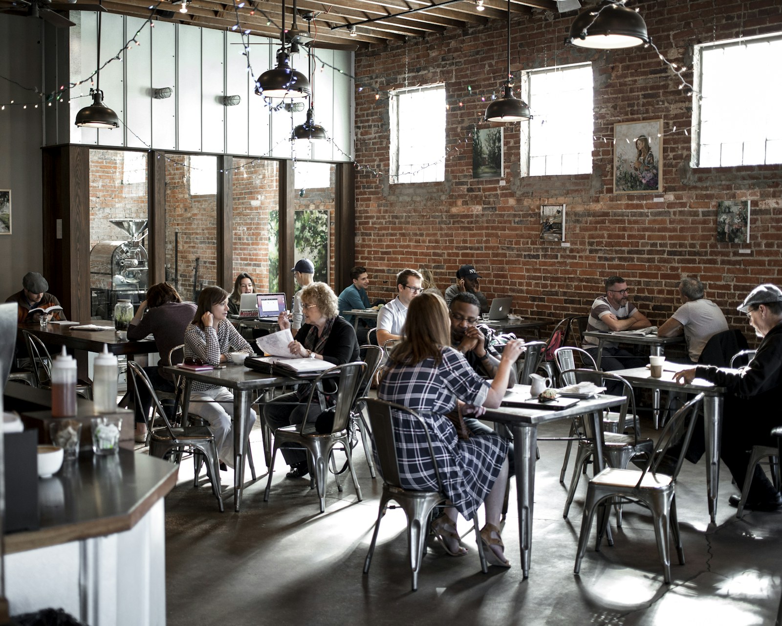 People sitting at tables in a busy daytime cafe, the kind of public place the safety checklist recommends.