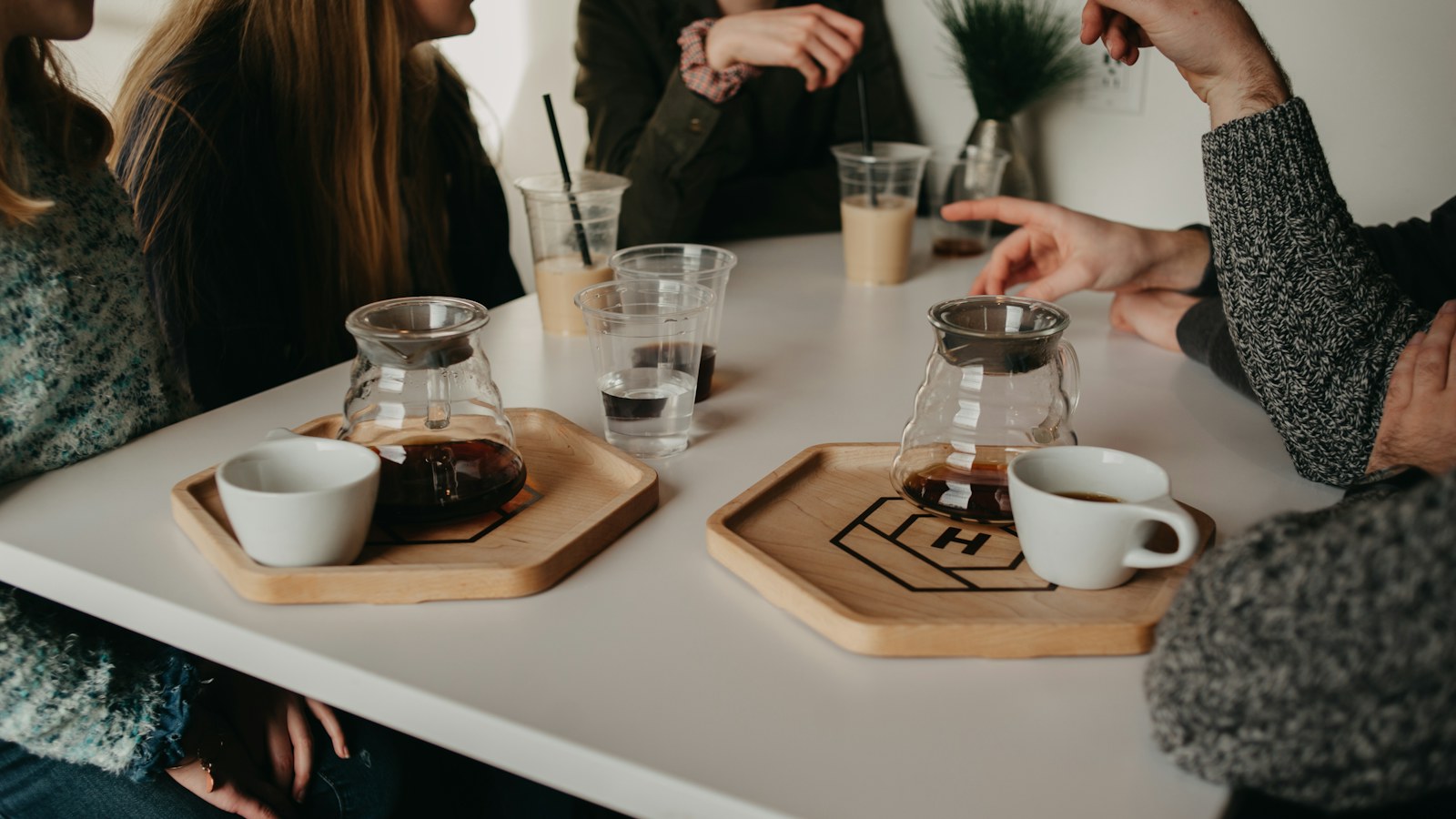 Friends talking over drinks and pastries at a café table.
