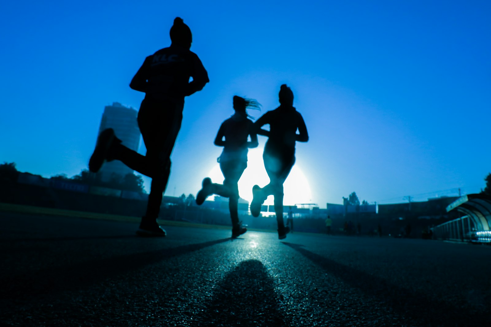 Three runners silhouetted against the light on a road at dawn