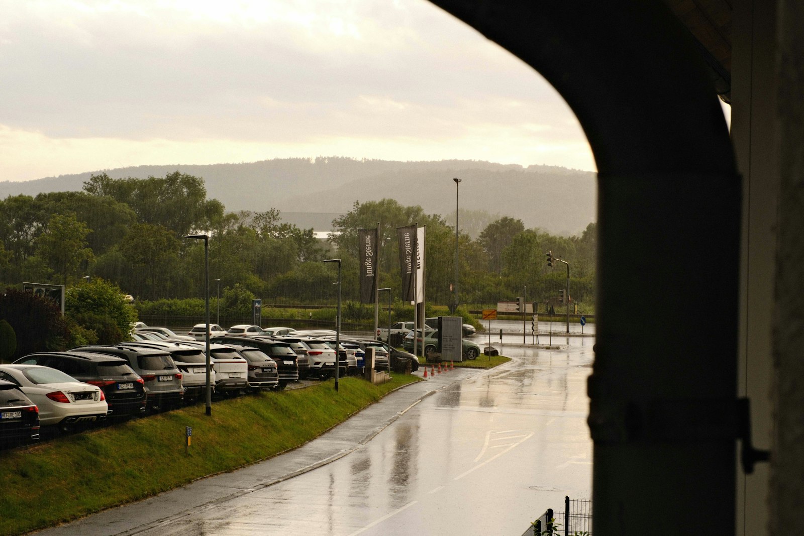 Rain falling over a green valley, wet road in the foreground