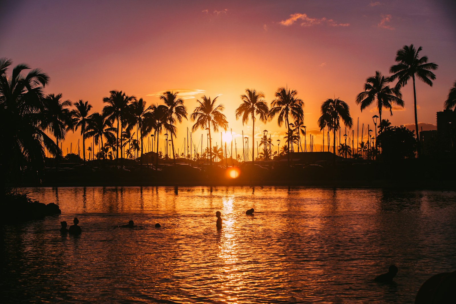 Palm trees silhouetted over a calm lagoon at sunset, one of the sunset spots on Oahu.