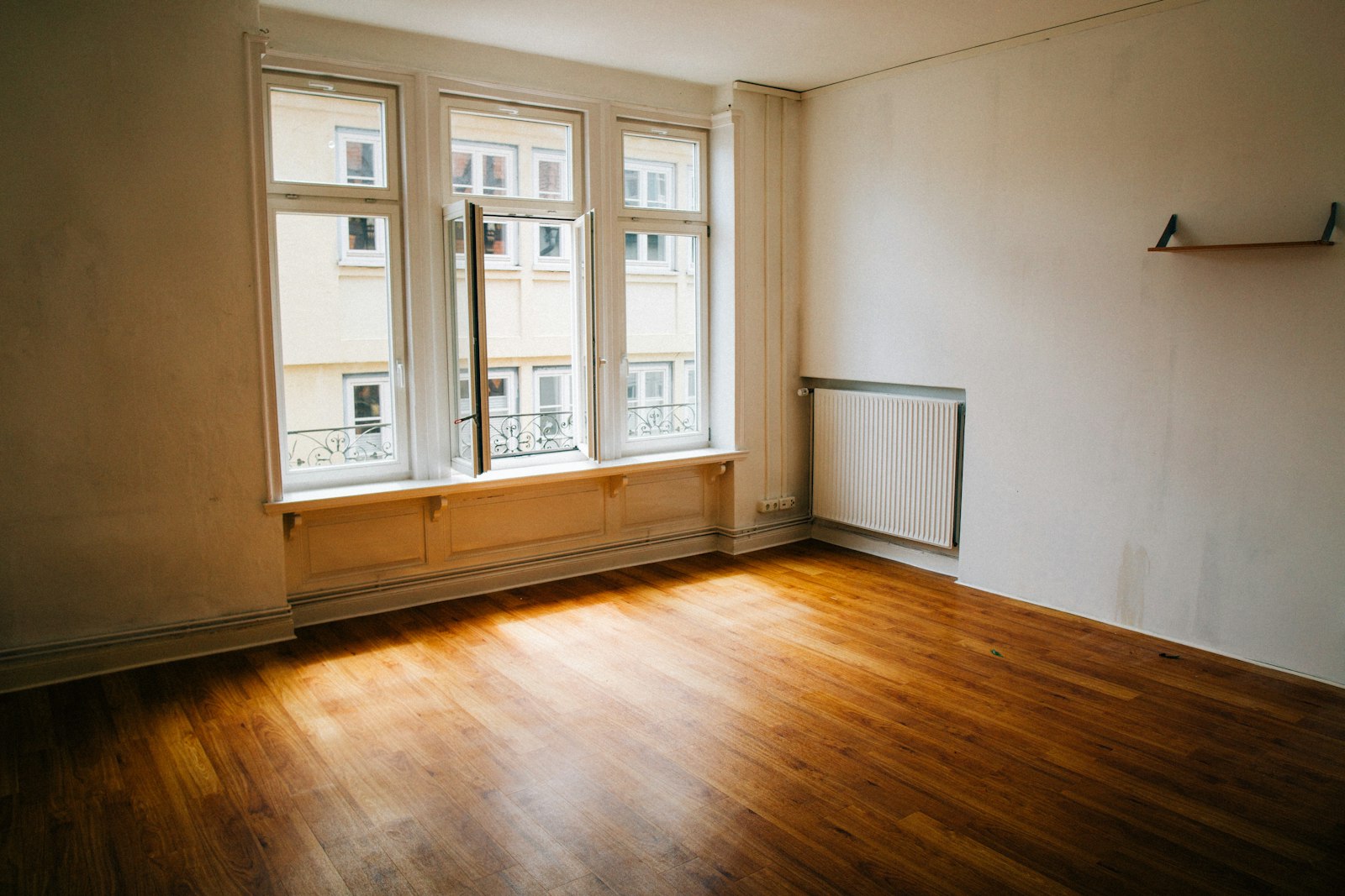 An empty room with bare wooden floors and tall windows, nothing unpacked in it yet.