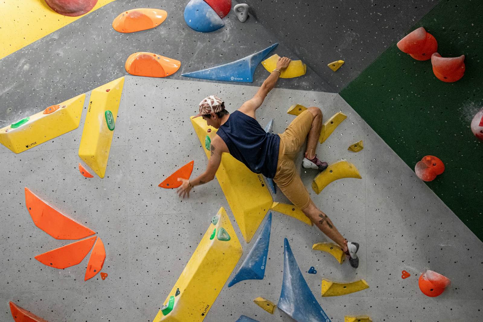 A climber on a colorful bouldering wall at an indoor gym, one of the drop-in fitness classes in Honolulu to try with a buddy.