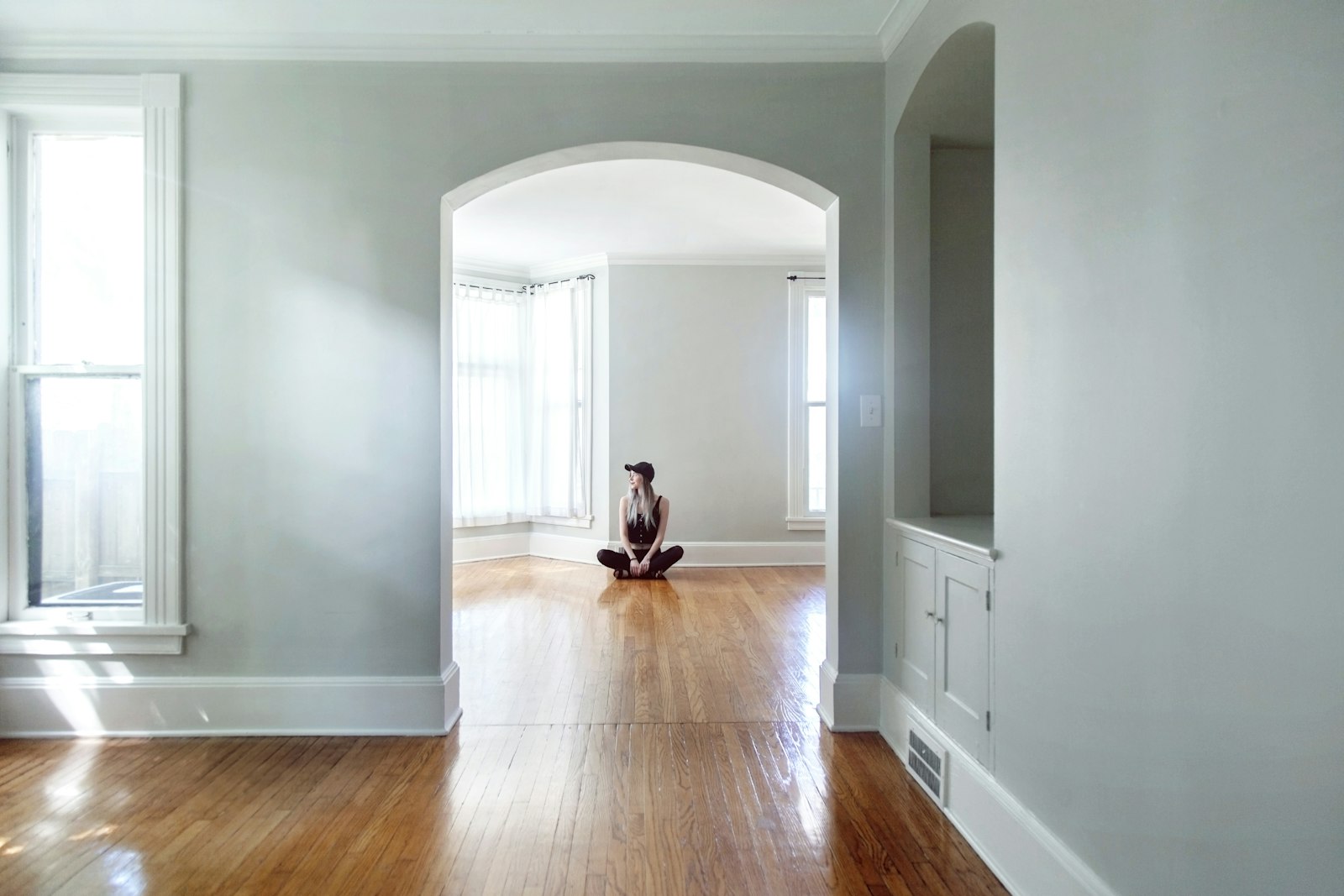 A person sitting alone on the floor of an empty house