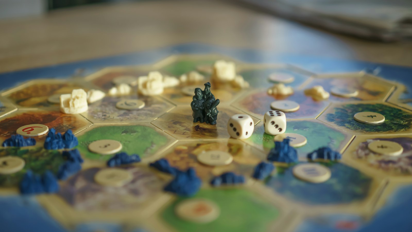 A board game laid out on a table in close focus, playing pieces and dice scattered across the tiles.