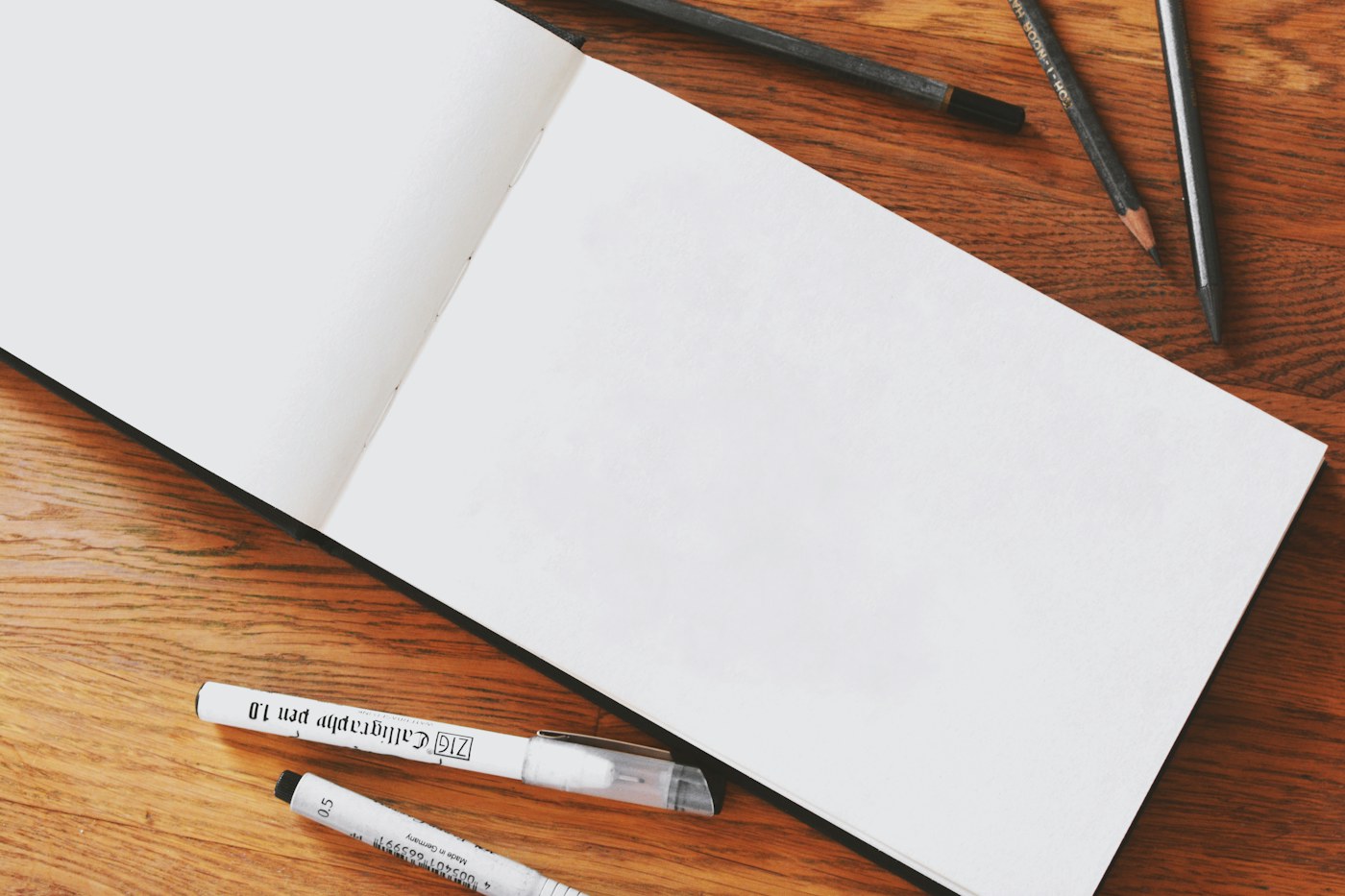 A blank sketchbook with drawing tools on a wooden table