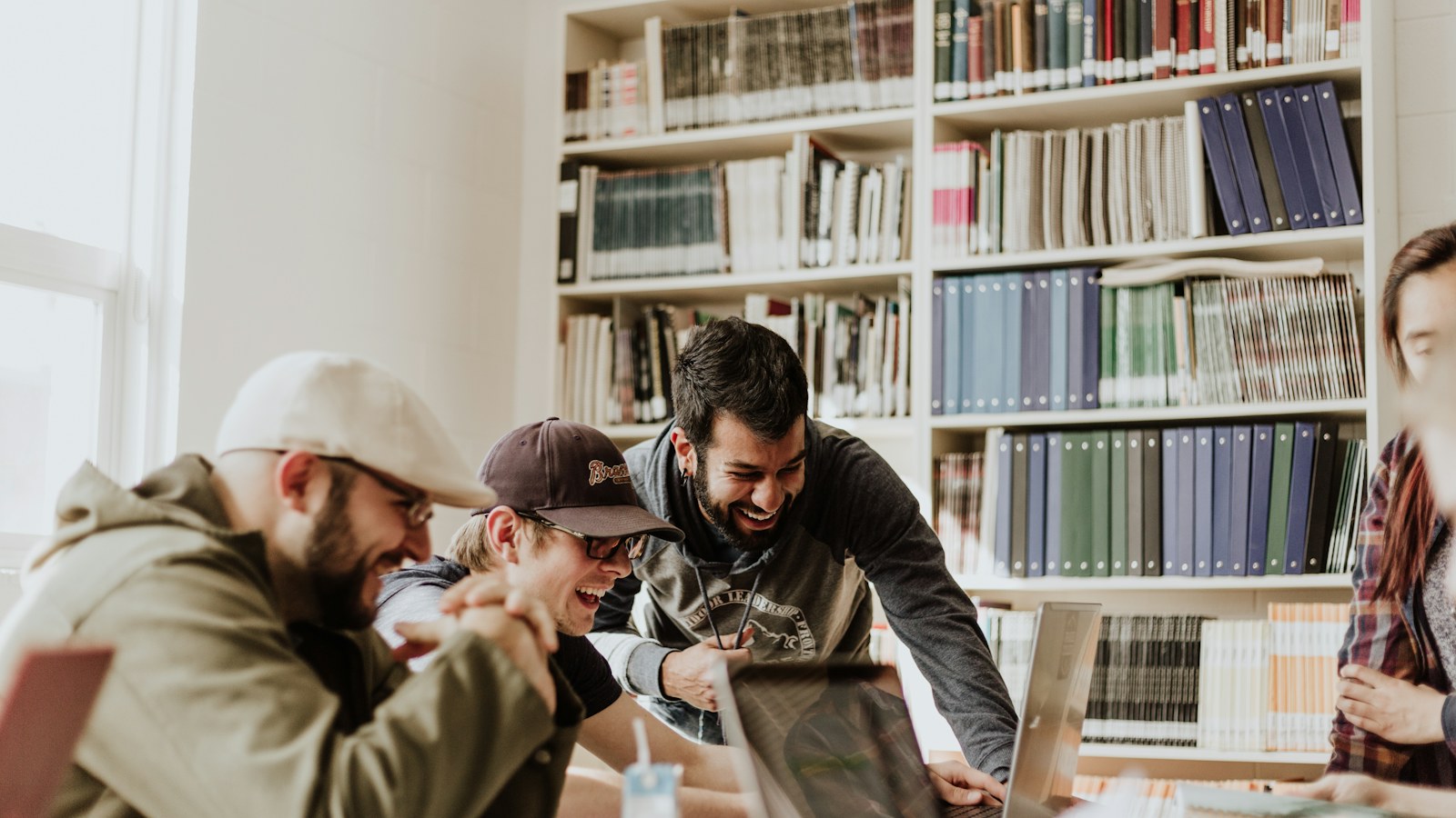 People working together at a table in front of library bookshelves.