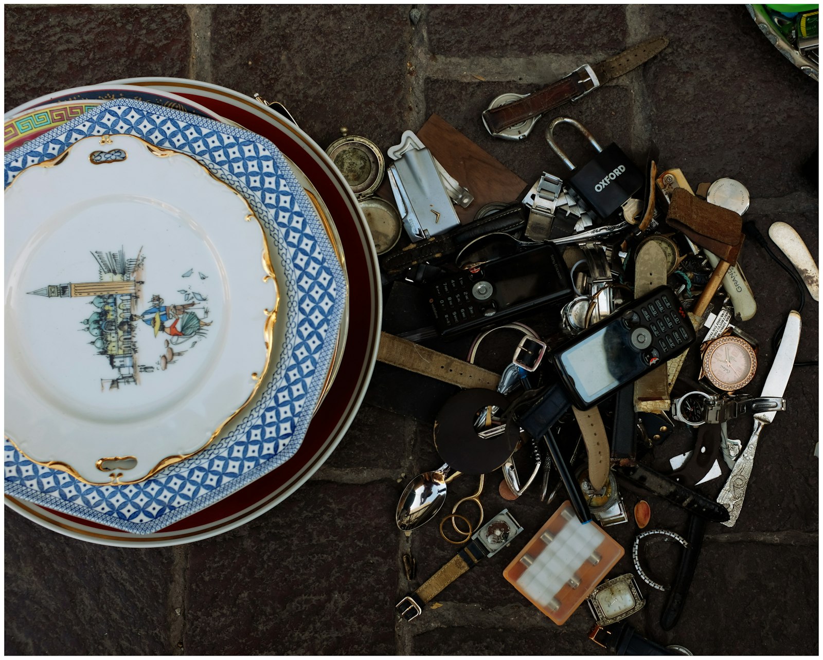 Secondhand watches, belts and china laid out on the ground at an open-air market