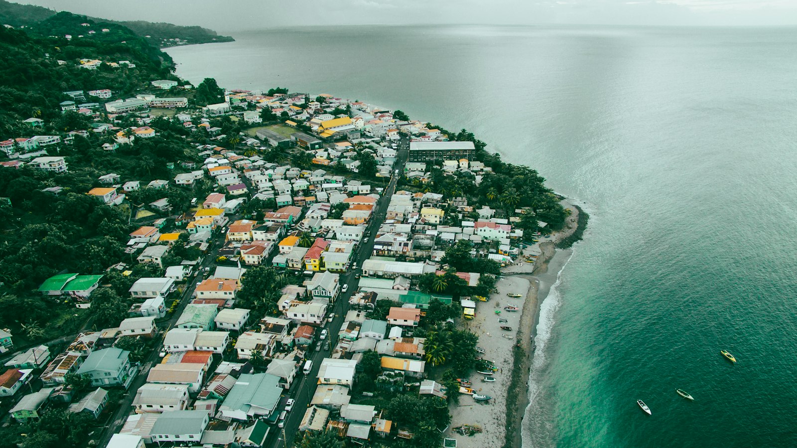A small coastal town seen from above, houses packed between the highway and a reef.