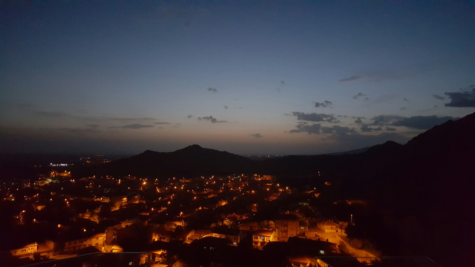 City lights spread out below a ridge at night