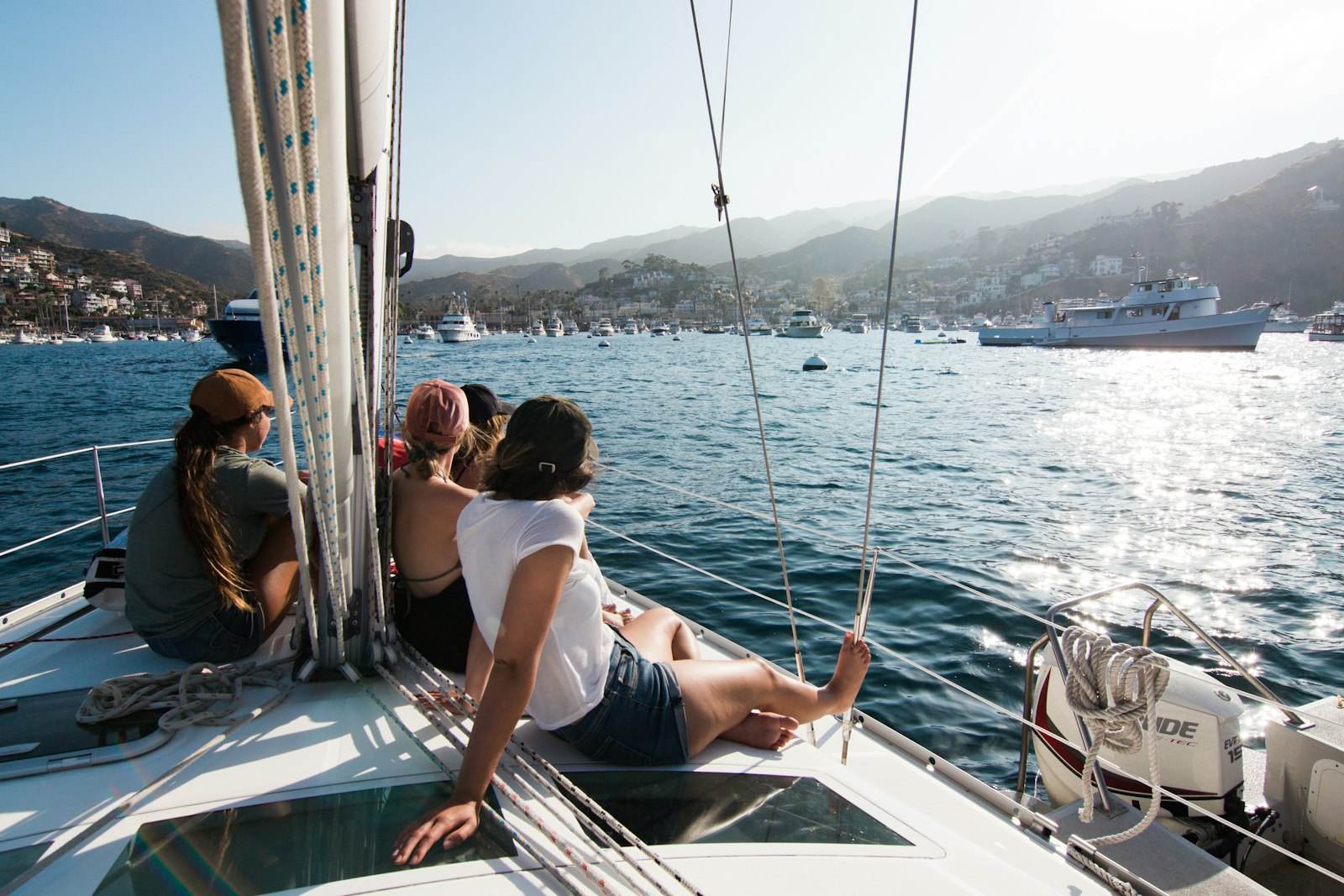 Four people sitting together on the deck of a sailing boat, all looking out at the water