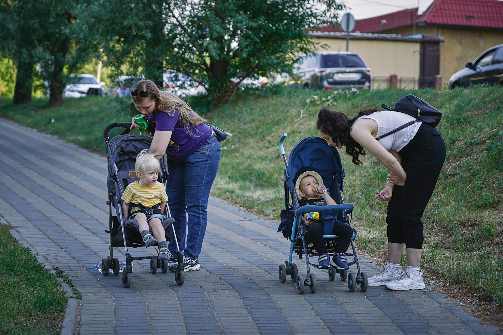 Two parents walking side by side pushing strollers