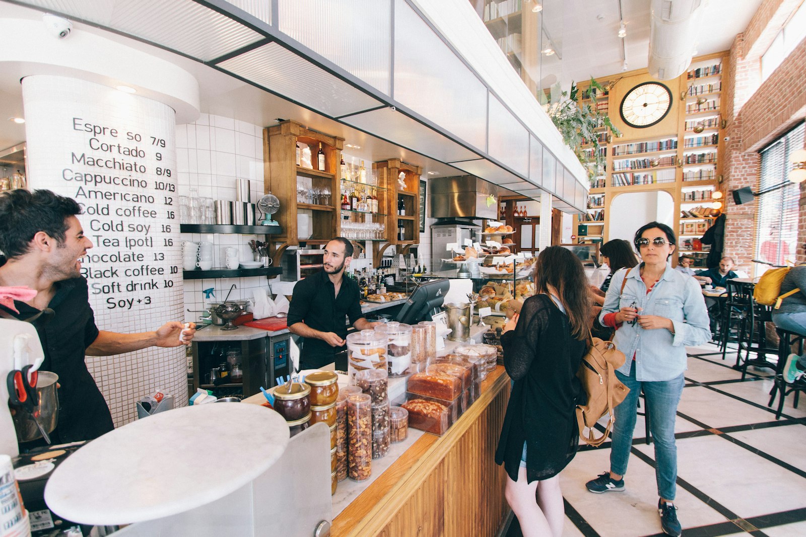 People standing and talking at the counter of a busy cafe