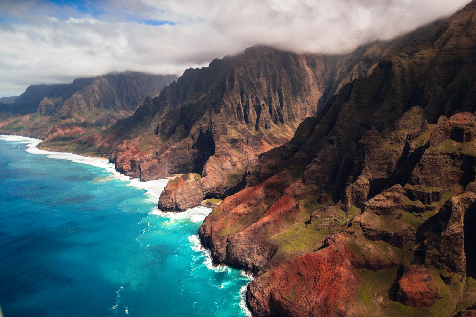 Aerial view of the Napali Coast cliffs and turquoise water on Kauai, Hawaii.